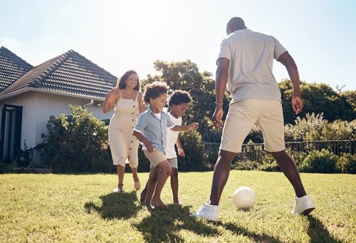Family Playing Soccer in Backyard